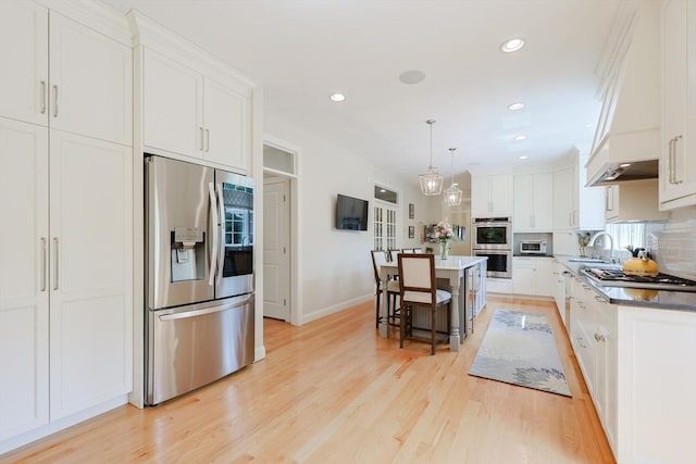 kitchen with stainless steel appliances, a sink, white cabinets, light wood finished floors, and recessed lighting