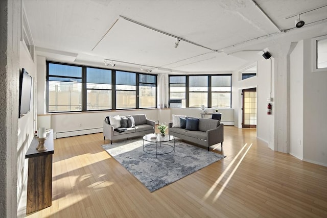 living room with a baseboard heating unit, light hardwood / wood-style floors, and track lighting