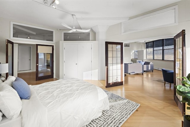 bedroom with lofted ceiling, track lighting, french doors, ceiling fan, and wood-type flooring