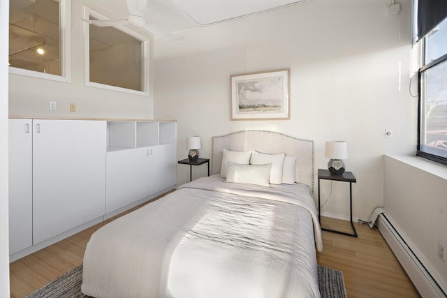 bedroom with hardwood / wood-style floors, ceiling fan, and baseboard heating