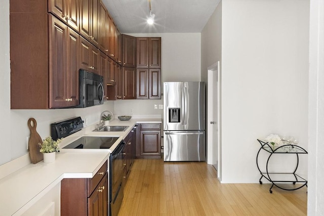 kitchen with stainless steel fridge, sink, light hardwood / wood-style flooring, and electric range oven