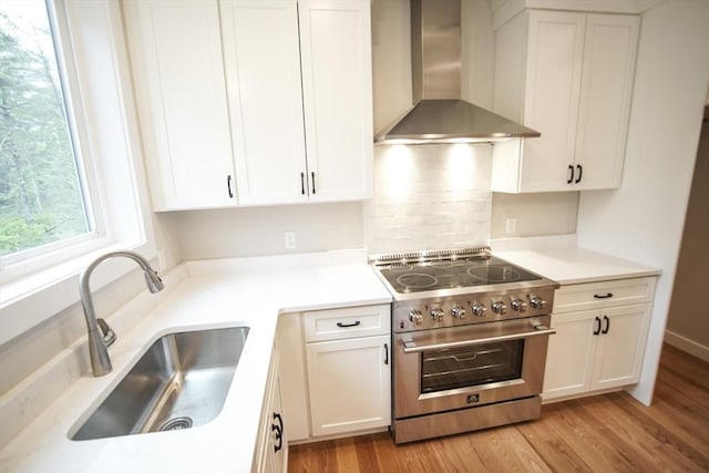 140 Tispaquin St, Middleboro, MA 02346 - kitchen featuring wall chimney range hood, stainless steel stove, a sink, and white cabinets