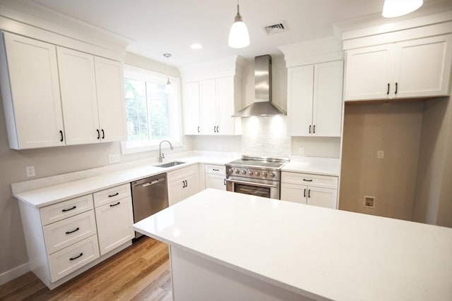 140 Tispaquin St, Middleboro, MA 02346 - kitchen featuring wall chimney range hood, stainless steel appliances, a sink, light wood finished floors, and pendant lighting
