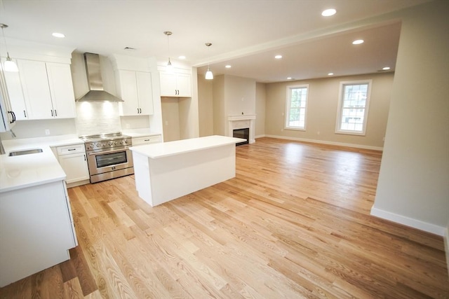 140 Tispaquin St, Middleboro, MA 02346 - kitchen with wall chimney exhaust hood, high end range, a center island, white cabinetry, and recessed lighting