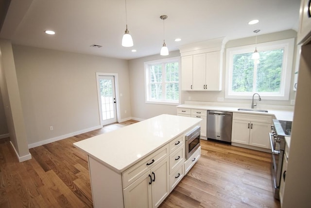 140 Tispaquin St, Middleboro, MA 02346 - kitchen with appliances with stainless steel finishes, a sink, hanging light fixtures, white cabinetry, and light countertops