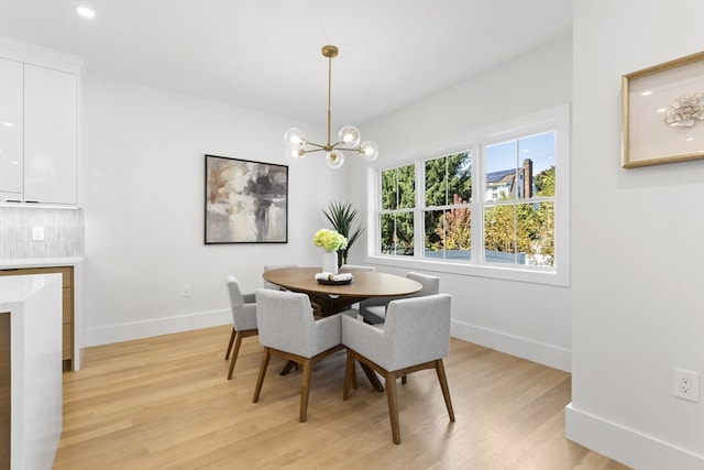 dining room with light wood-type flooring and an inviting chandelier