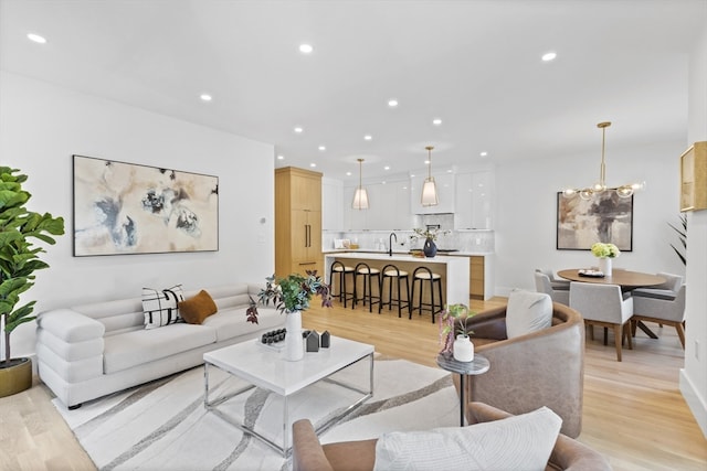 living room with a chandelier, sink, and light hardwood / wood-style flooring