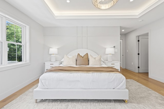 bedroom featuring light hardwood / wood-style floors and a raised ceiling