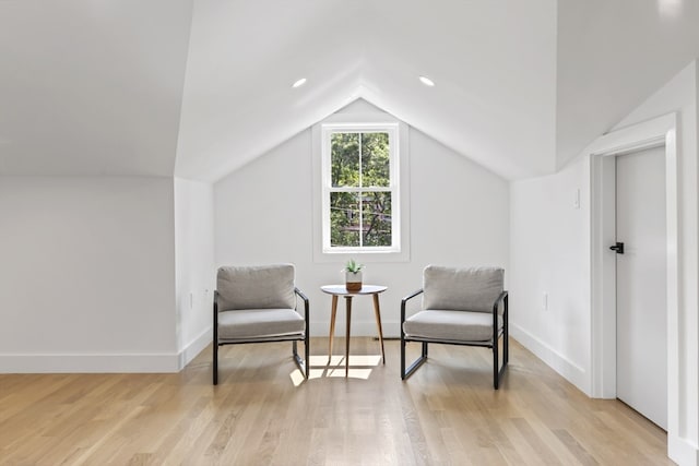 living area featuring light wood-type flooring and vaulted ceiling