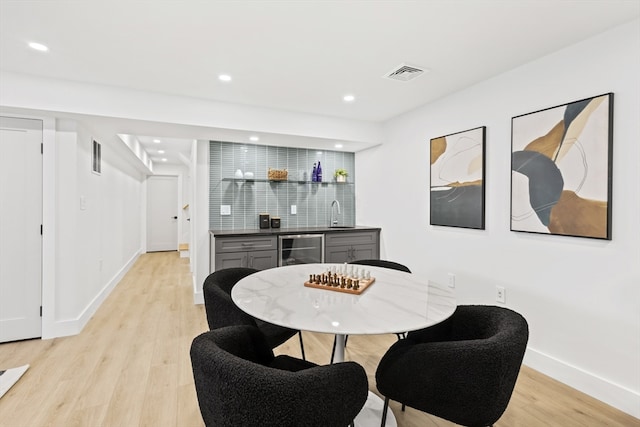 dining area featuring wine cooler, bar area, and light hardwood / wood-style floors