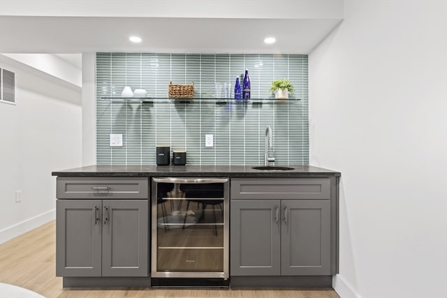 bar with gray cabinets, sink, light wood-type flooring, and wine cooler