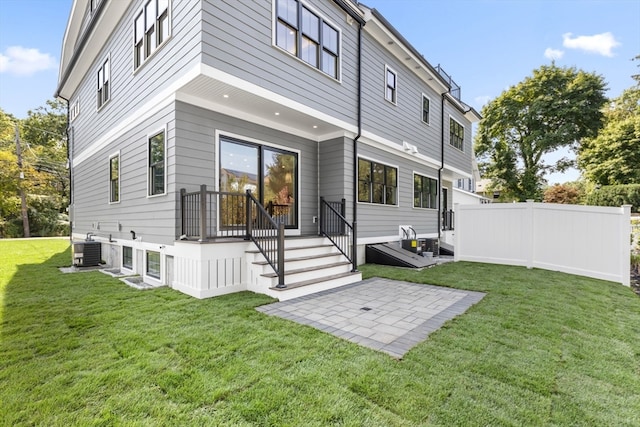 back of house featuring central air condition unit and a yard