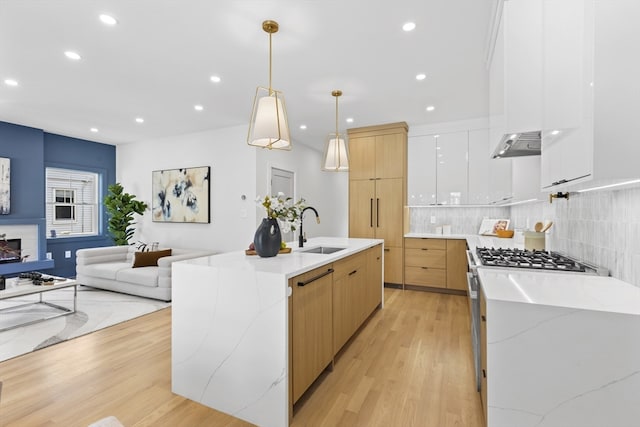 kitchen with hanging light fixtures, white cabinetry, sink, and a spacious island