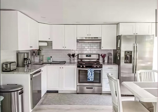 31 Northern Ave, Dennis, MA 02639 - kitchen featuring stainless steel appliances, under cabinet range hood, white cabinetry, backsplash, and light wood finished floors
