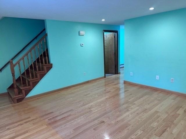 30 Wallace Cir Unit 30, Malden, MA 02148 - unfurnished living room featuring wood finished floors, stairway, recessed lighting, baseboards, and a baseboard radiator