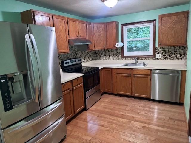 30 Wallace Cir Unit 30, Malden, MA 02148 - kitchen with stainless steel appliances, a sink, under cabinet range hood, light wood finished floors, and brown cabinets