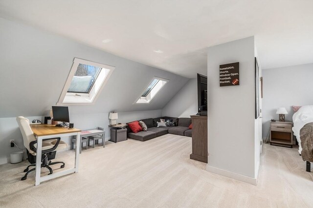 office space featuring light carpet, lofted ceiling with skylight, and baseboards