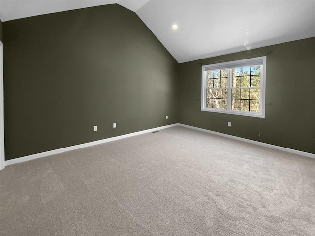 empty room with light carpet, vaulted ceiling, and baseboards