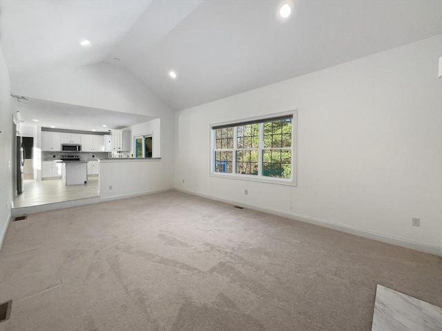 unfurnished living room with light carpet, high vaulted ceiling, baseboards, and recessed lighting