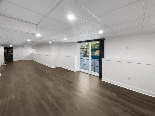 below grade area with an AC wall unit, dark wood-type flooring, recessed lighting, and baseboards