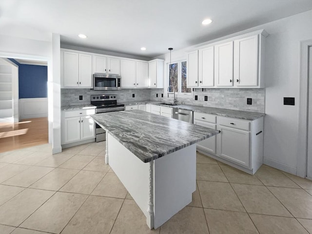 kitchen with light tile patterned floors, appliances with stainless steel finishes, a sink, and white cabinets