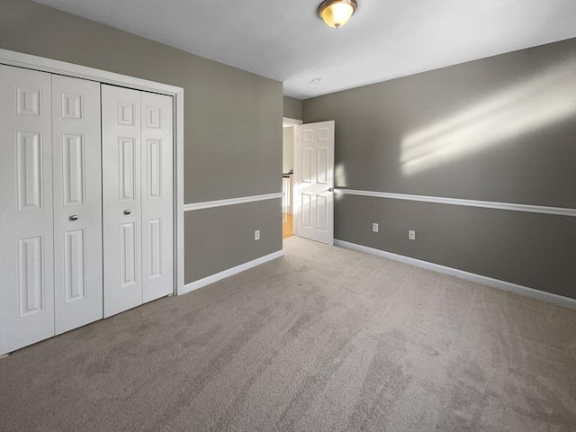 unfurnished bedroom with carpet floors, a closet, and baseboards