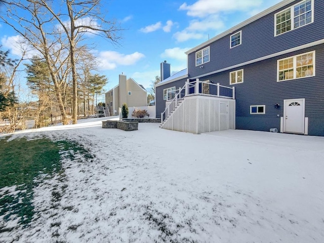 snow covered rear of property with stairway