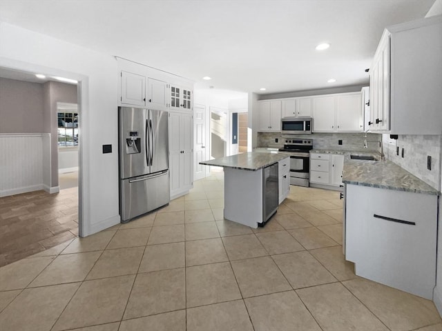 kitchen featuring a wainscoted wall, stone countertops, light tile patterned floors, and stainless steel appliances