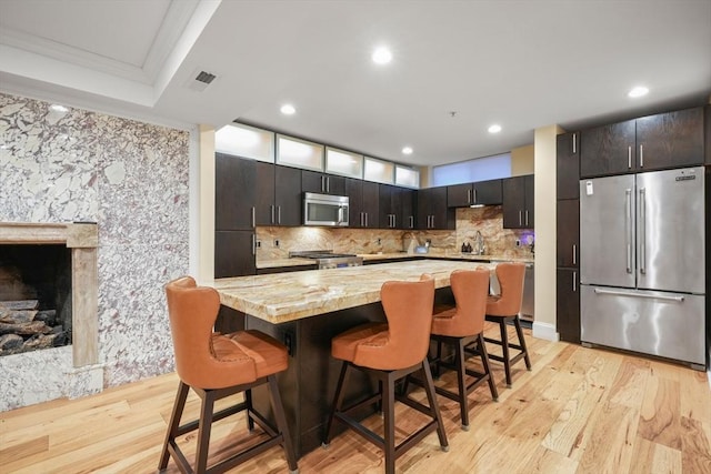 kitchen with visible vents, appliances with stainless steel finishes, a sink, light wood-type flooring, and a kitchen breakfast bar