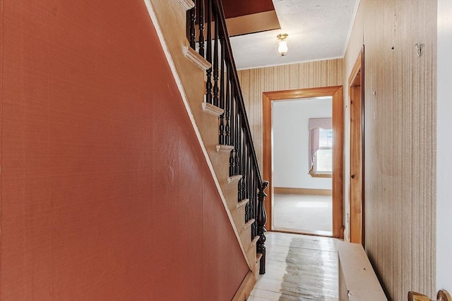 interior space featuring wallpapered walls, stairs, baseboards, and crown molding