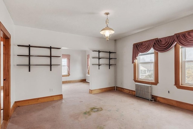 unfurnished room featuring carpet floors, radiator heating unit, baseboards, and a wealth of natural light