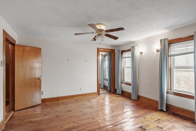 empty room with light wood finished floors, plenty of natural light, and baseboards