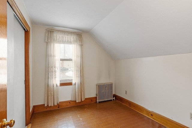 bonus room with radiator heating unit, baseboards, vaulted ceiling, and wood finished floors