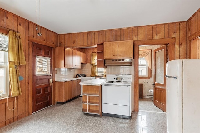 kitchen with white appliances, washer / clothes dryer, wood walls, under cabinet range hood, and open shelves