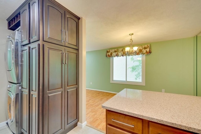 3 Concord Greene Unit 4, Concord, MA 01742 - kitchen with stacked washer / dryer, a chandelier, baseboards, light stone countertops, and pendant lighting