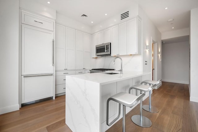 700 Harrison Ave Unit Ph-610, Boston, MA 02118 - kitchen featuring stainless steel microwave, a peninsula, a sink, baseboards, and white cabinetry