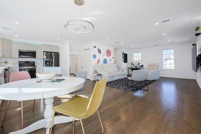 dining area featuring dark wood-type flooring and crown molding