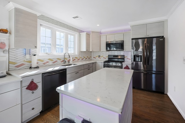 kitchen featuring dark wood-type flooring, stainless steel appliances, sink, light stone countertops, and a center island