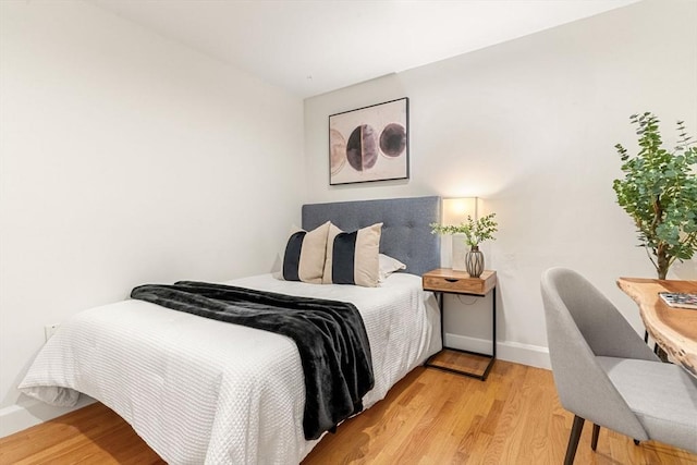 bedroom with light wood finished floors and baseboards