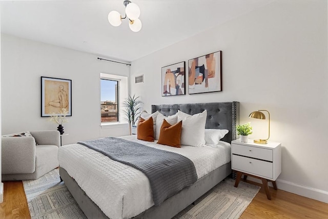 bedroom with light wood finished floors, a chandelier, and baseboards
