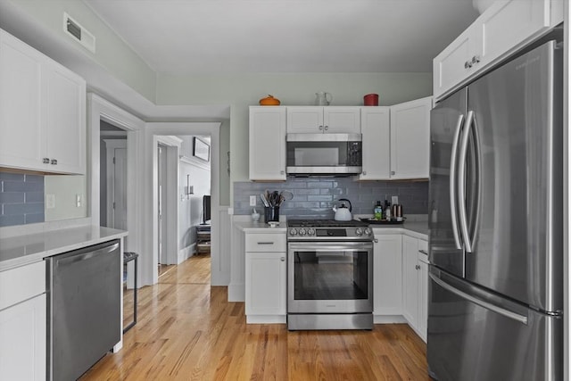 40 King St Unit 3, Boston, MA 02122 - kitchen featuring stainless steel appliances, white cabinets, light countertops, light wood-style flooring, and backsplash