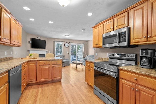 kitchen with stainless steel appliances, light hardwood / wood-style flooring, and kitchen peninsula