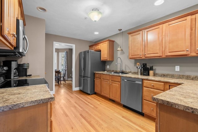 kitchen featuring appliances with stainless steel finishes, sink, hanging light fixtures, and light wood-type flooring