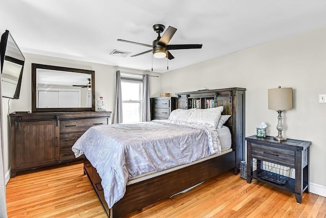 bedroom with light wood-style floors, baseboards, visible vents, and a ceiling fan