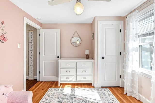 bedroom with a ceiling fan, light wood-style flooring, and baseboards