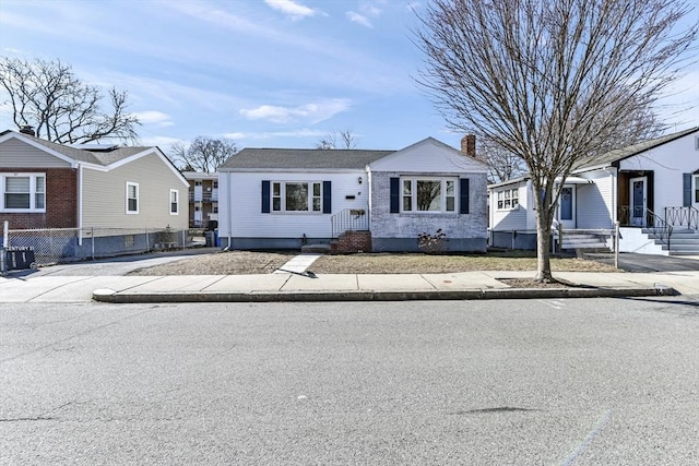 view of front of home featuring a residential view, fence, and a chimney