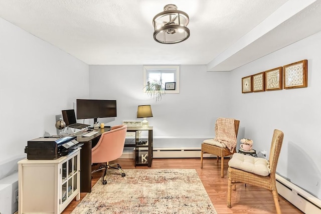 home office featuring a textured ceiling, baseboard heating, and wood finished floors