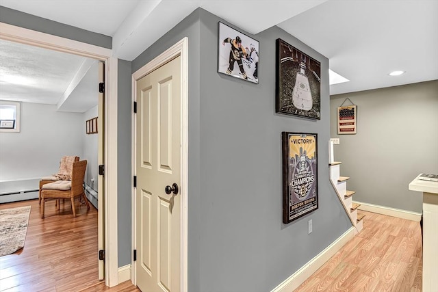 corridor featuring recessed lighting, stairway, light wood-style flooring, a baseboard heating unit, and baseboards