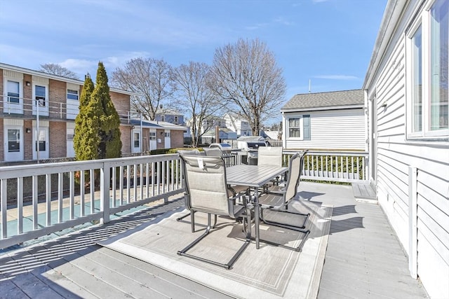 wooden terrace featuring a residential view, a fenced in pool, and outdoor dining space