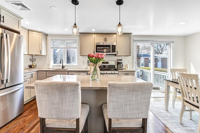 kitchen featuring visible vents, dark wood-style floors, light stone countertops, stainless steel appliances, and a sink